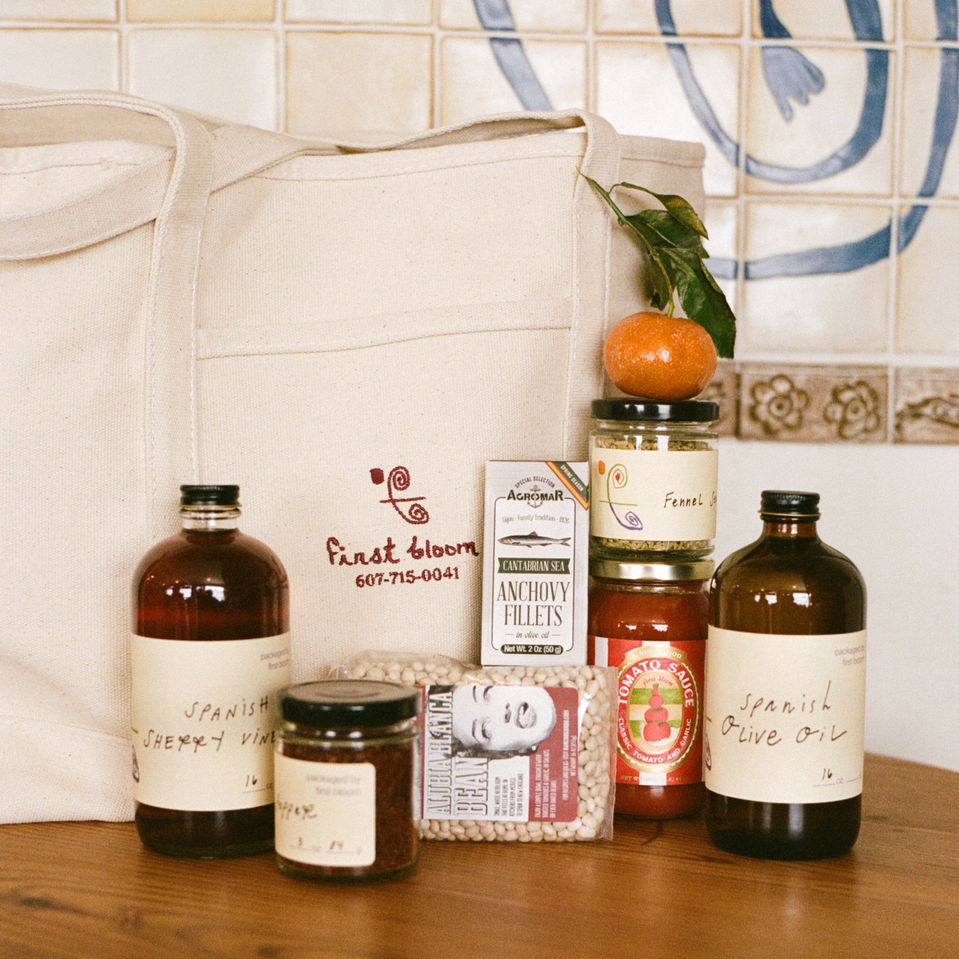 Assorted jars and bottles on a wooden surface with a tiled wall in the background