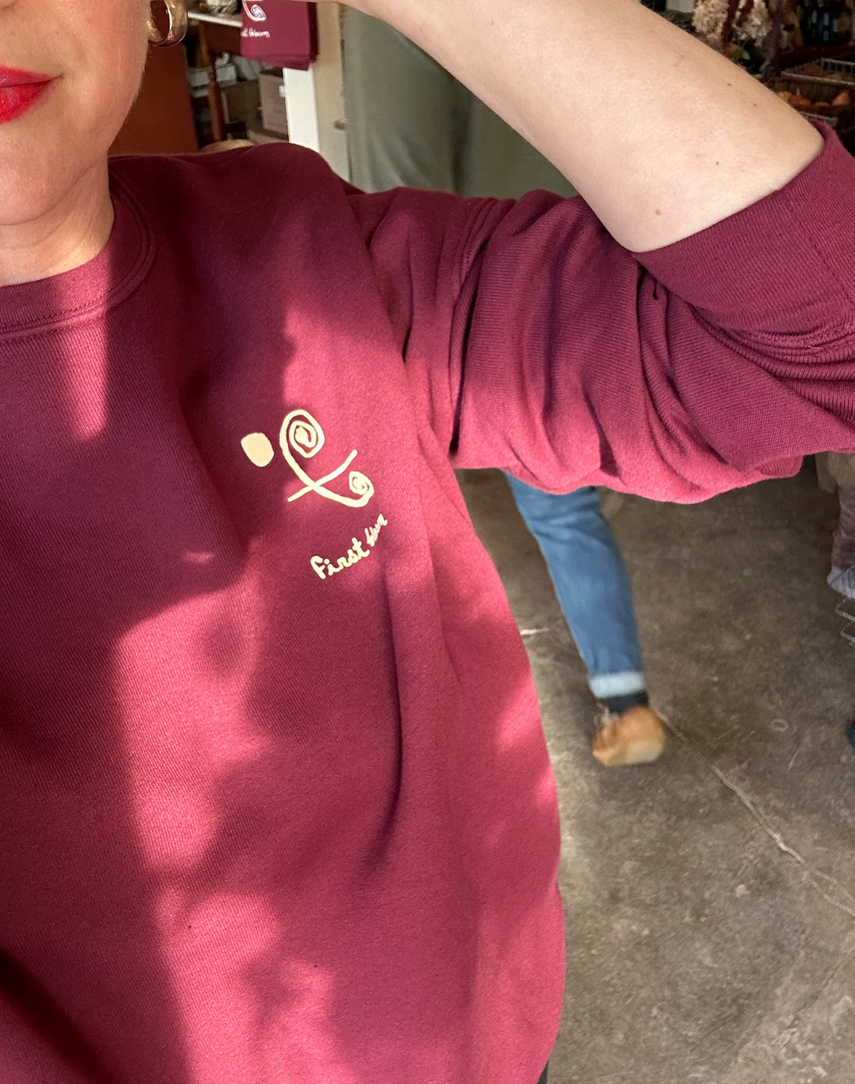 A person wearing a red Champion crewneck sweatshirt with white text and logo on the front.