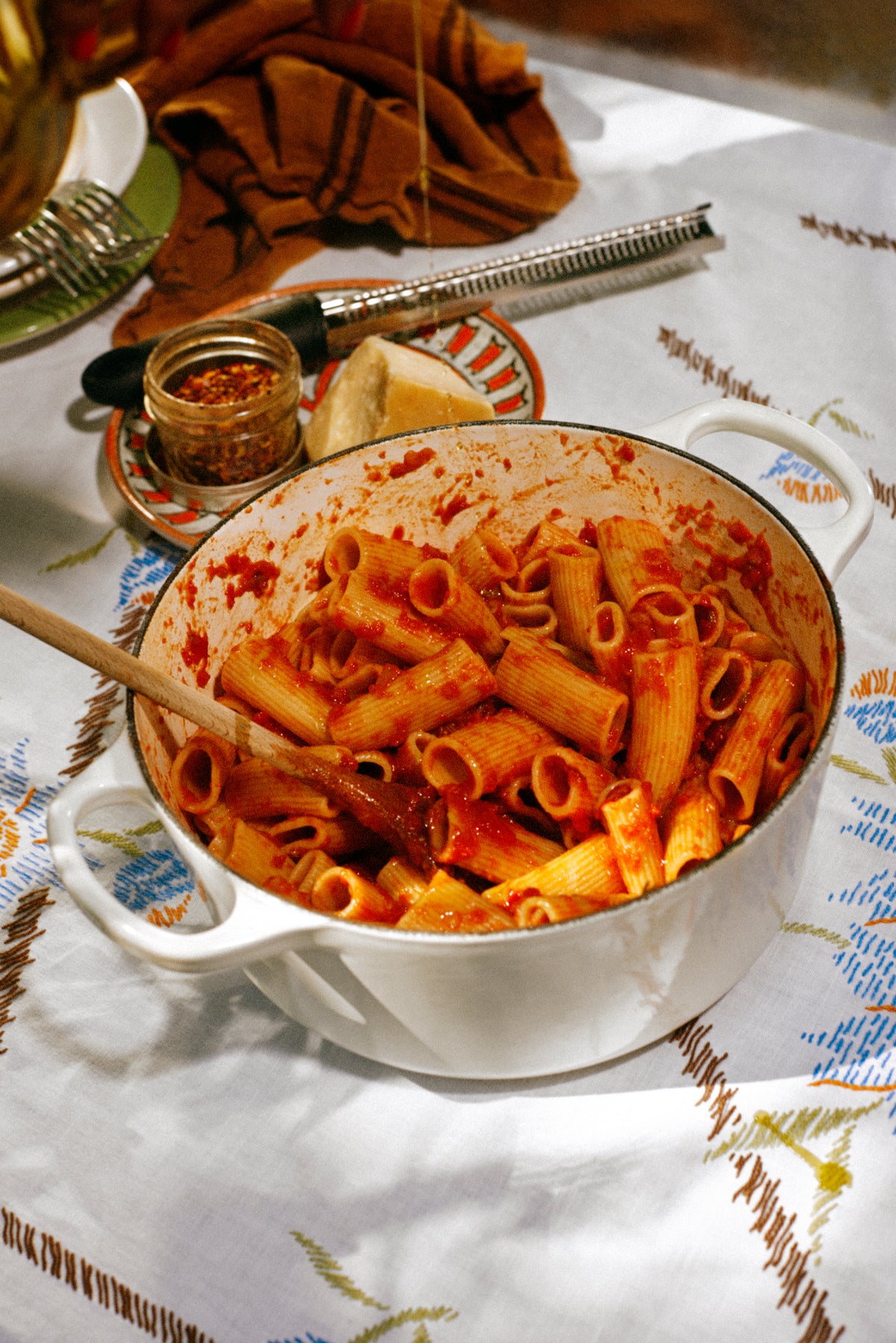 Bowl of pasta with a wooden spoon on a patterned tablecloth