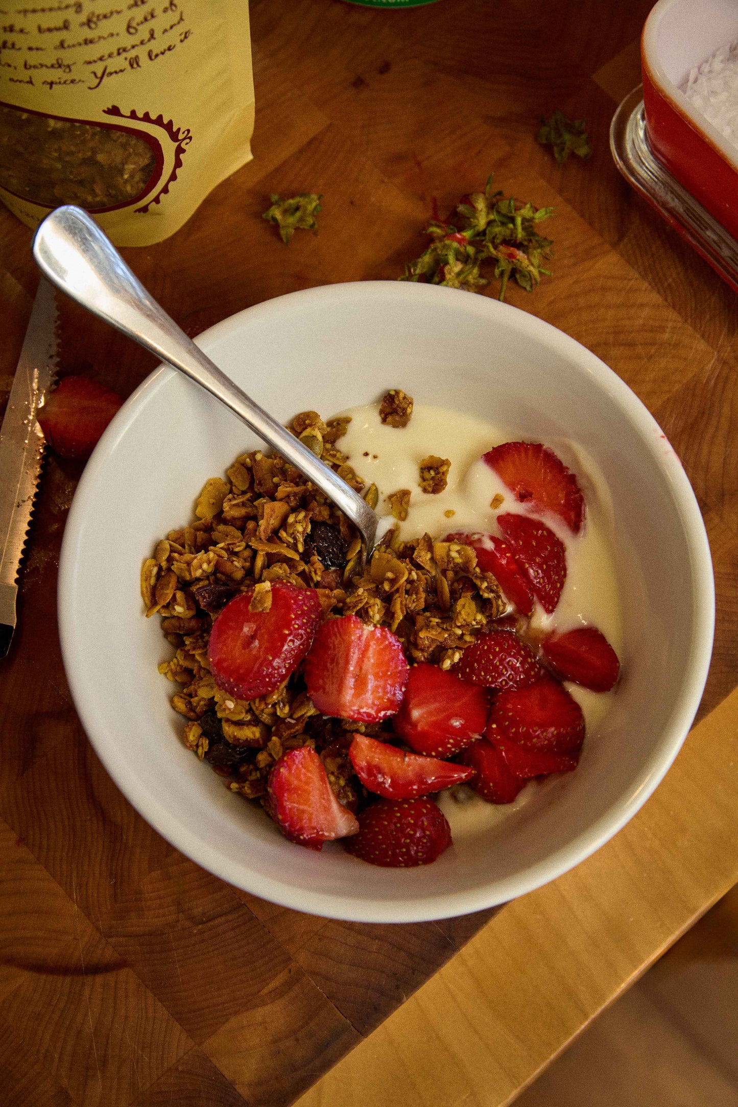 Bowl of granola with strawberries and yogurt on a wooden table