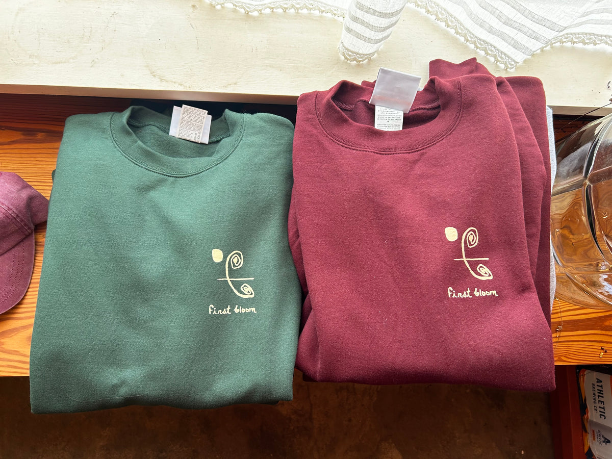 Folded crew First Bloom sweatshirts in sage and maroon